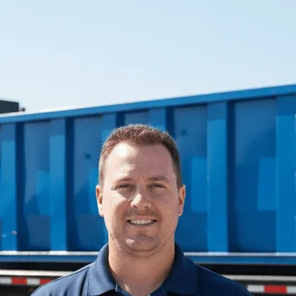 Tyler Bennett, Lead Driver at Cape Coral Brothers Dumpster Rental, standing by a company rolloff truck